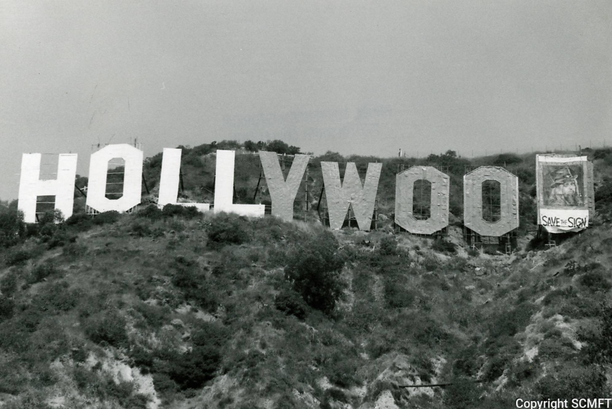 1973. Знак Голливуд в аварийном состоянии. Баннер «сохрани знак» закрывает букву D.